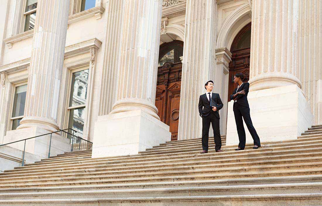 Two business professionals standing on the stairs of a government building discussing OECD transfer pricing rules.