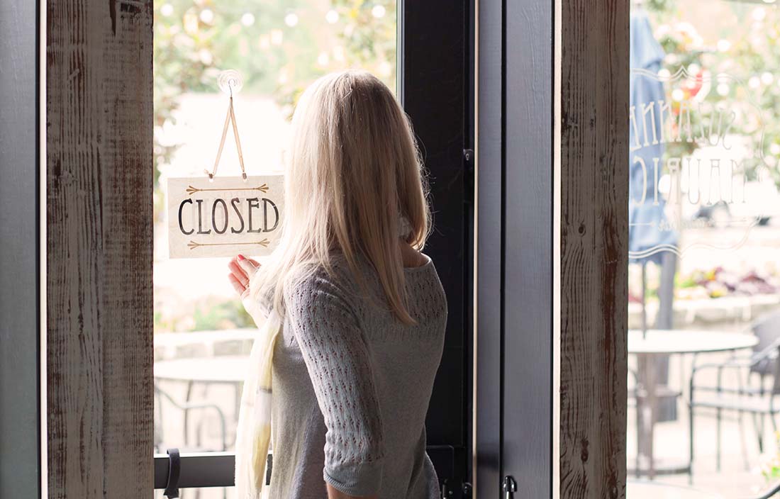 Woman flipping sign to "closed" for her small business. 