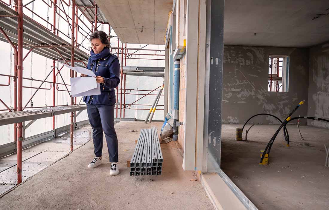 Woman standing at a construction site looking at blueprints
