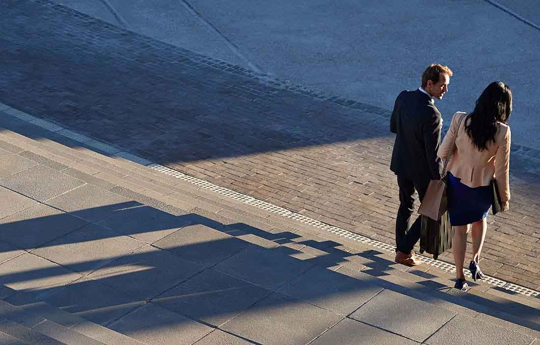 Two business professionals walking down a set of steps together.