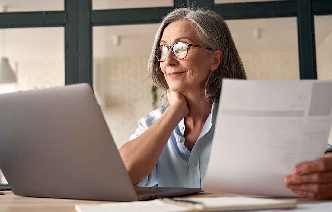 Elderly woman reviewing long term care insurance options on her laptop computer.