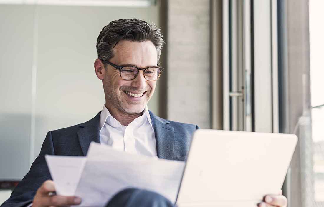Business professional smiling while looking at documents.