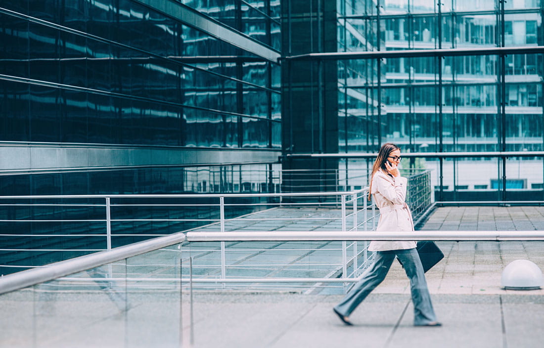 Business professional walking on a sidewalk near a glass building