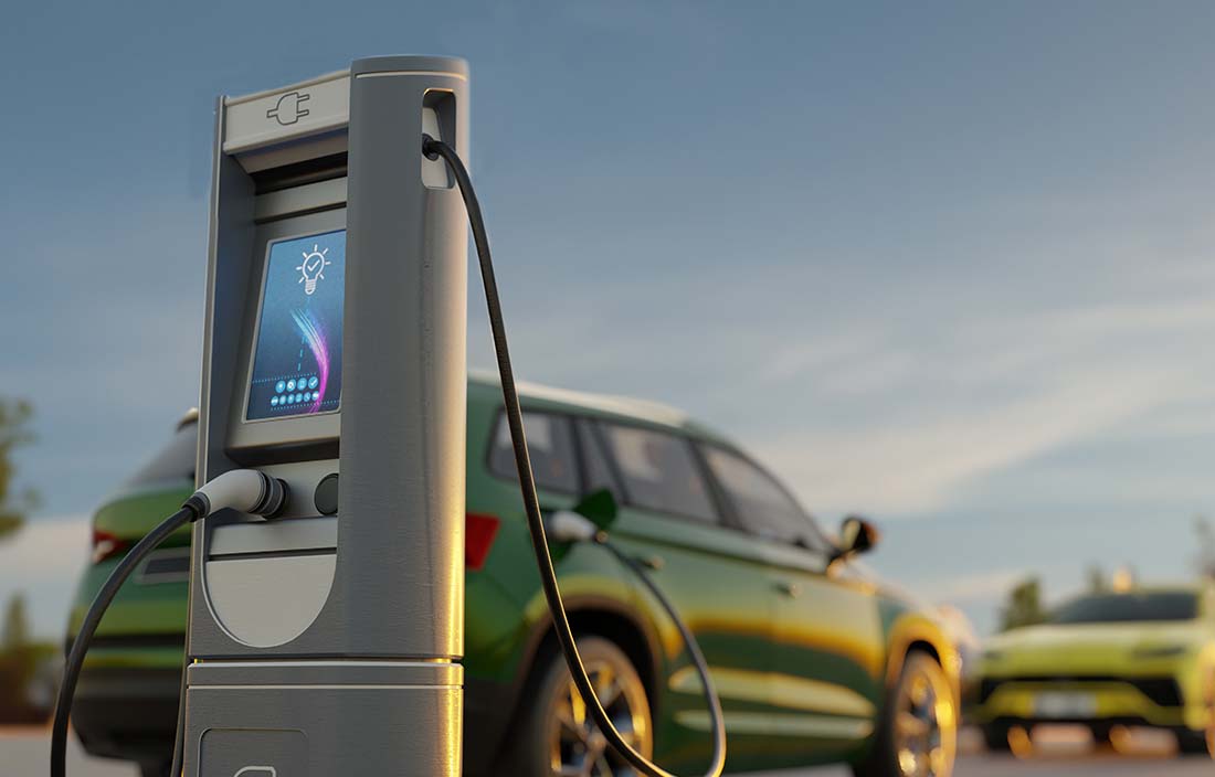Close up photo of an EV car charging station and a green SUV car