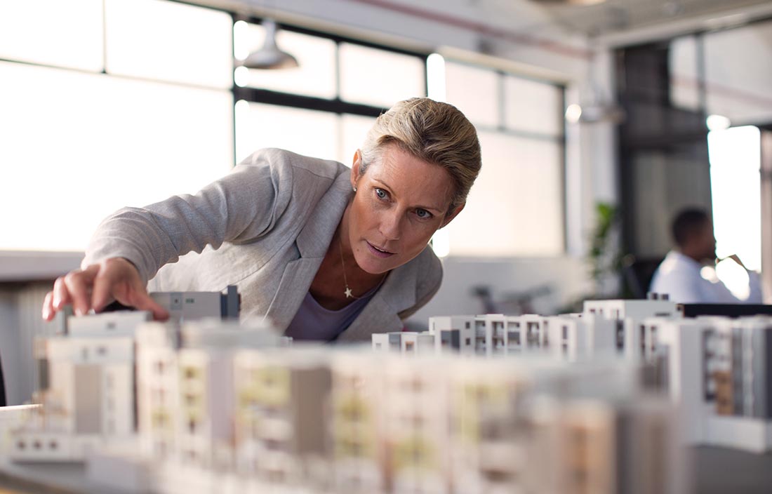Caucasian female real estate developer examining public-private development structural model in an office