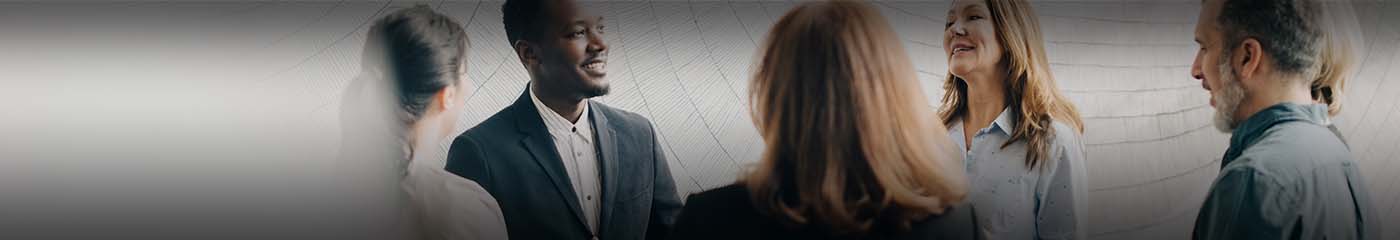 A group of racially diverse business professionals talking and smiling.