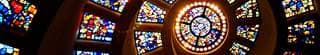 View looking up at a stained-glass chapel ceiling.
