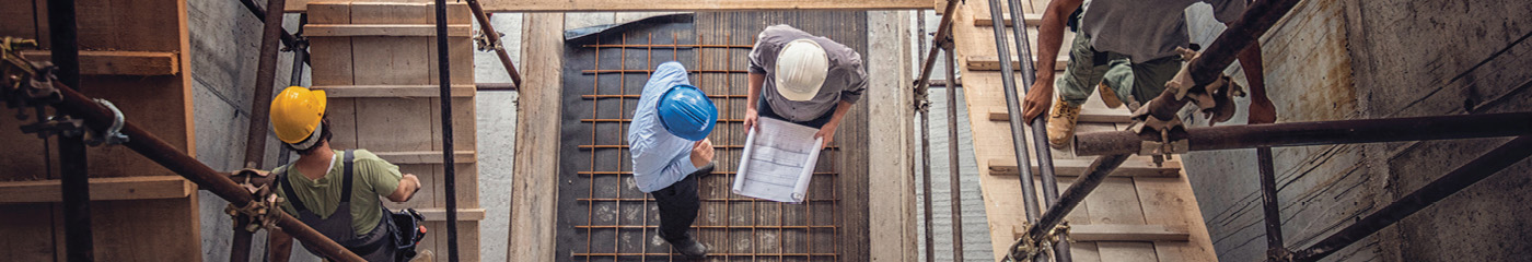 Top-down view of construction workers walking up wood ramps at a building site