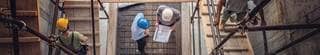 Top-down view of construction workers walking up wood ramps at a building site