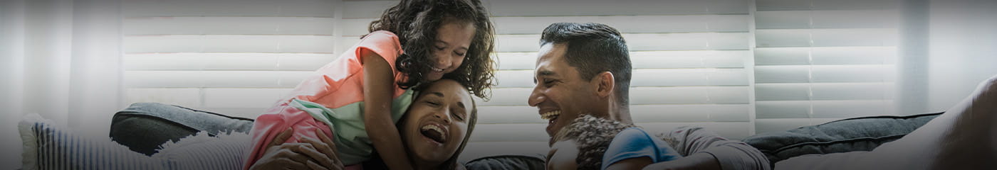 Family laughing with their kids on the couch.