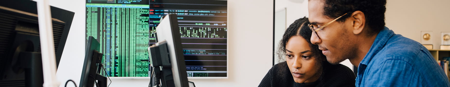 Business professionals viewing a monitor screen together.