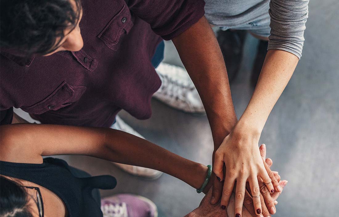 Image of three people putting their hands on top of each other