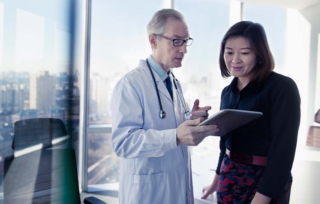 Doctor holding a tablet discussing results with a colleague.