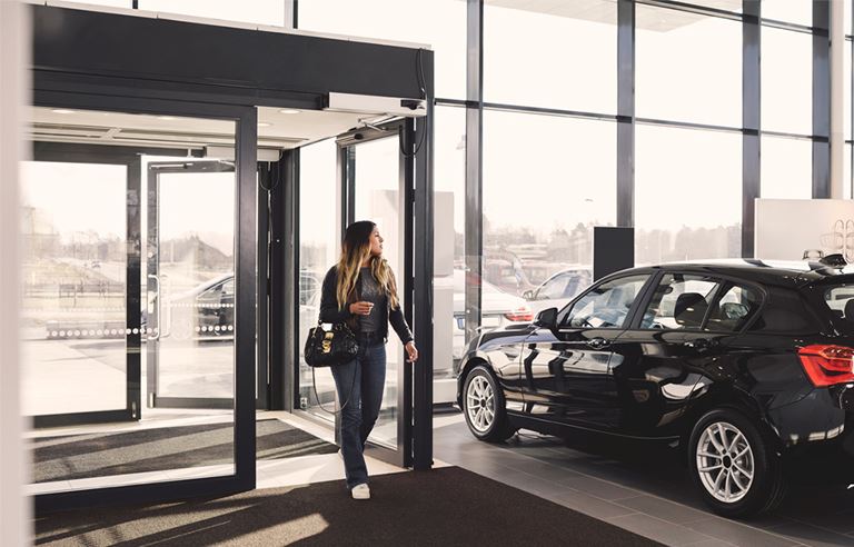 Image of woman walking into car dealership
