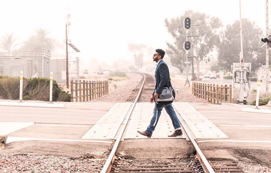 image of man crossing train tracks