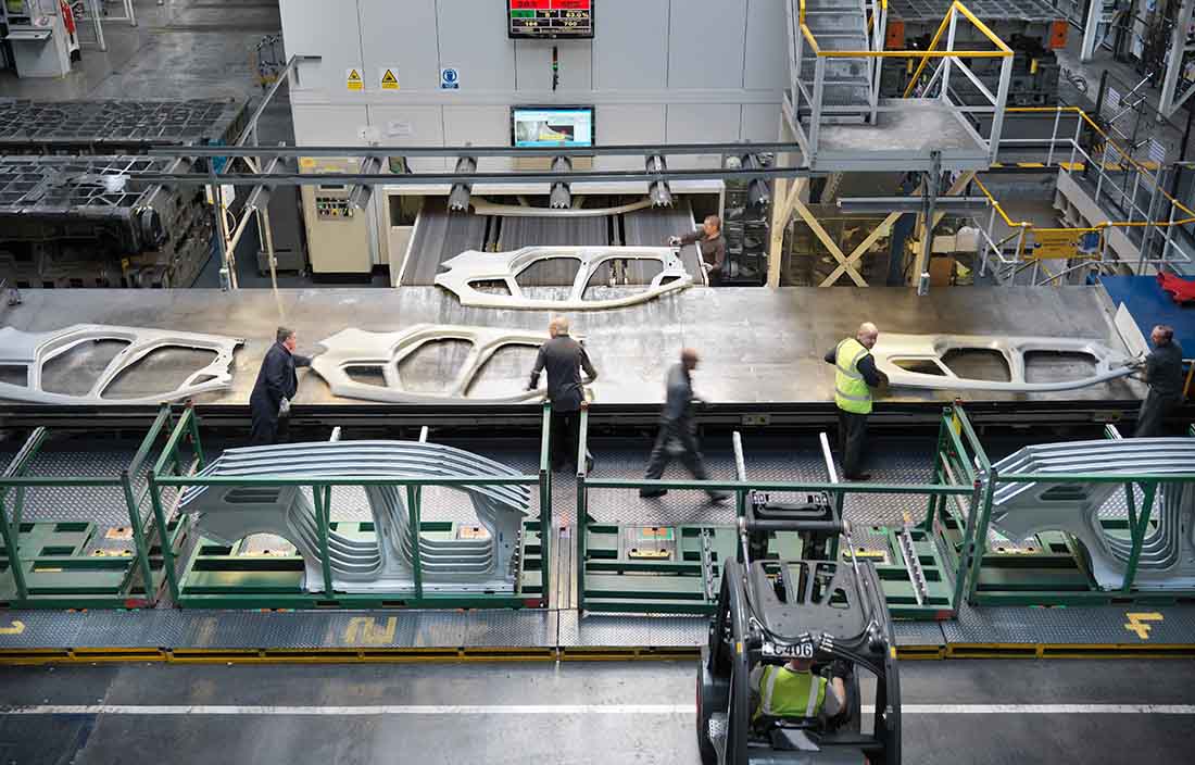 Manufacturing workers with automotive pieces in a factory.