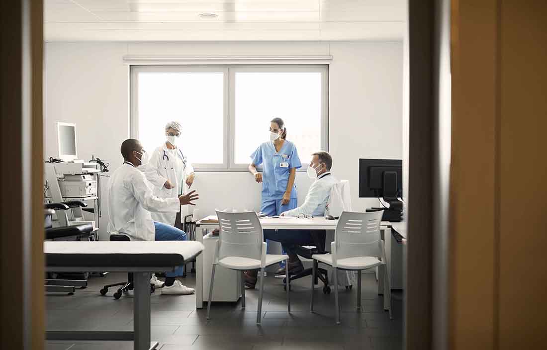 Group of hospitals and nurses talking in hospital room.