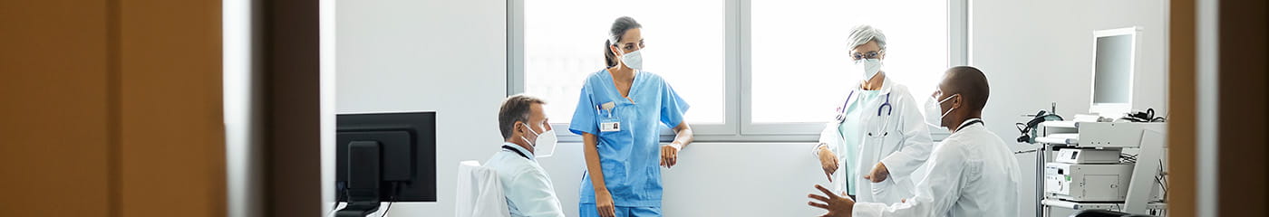 Group of doctors and nurses talking in hospital room.