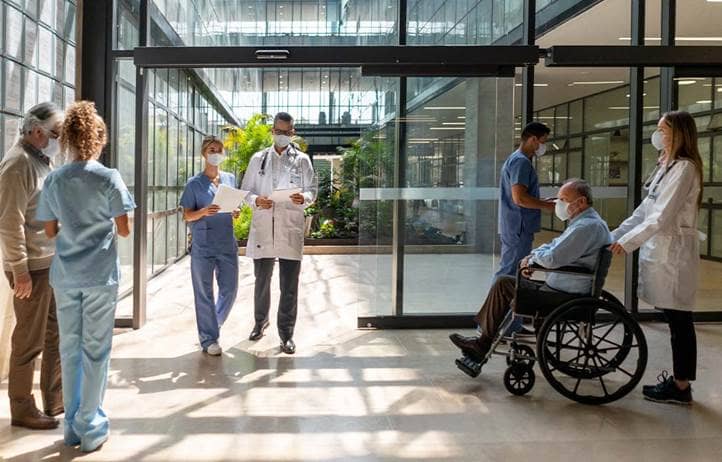 Nurses, doctors, and patients walking through a hospital lobby.