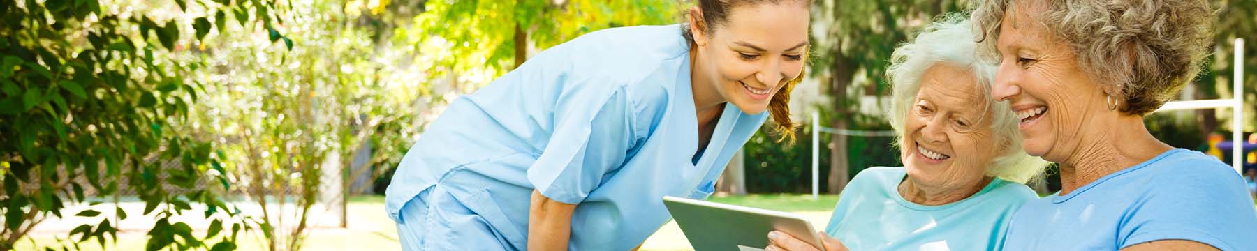 Elderly patient and a family member using a tablet handheld device while smiling.