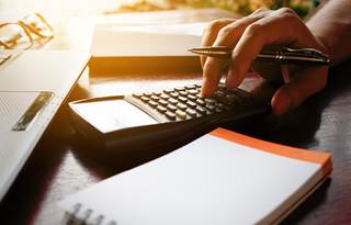 Image of hand typing on calculator