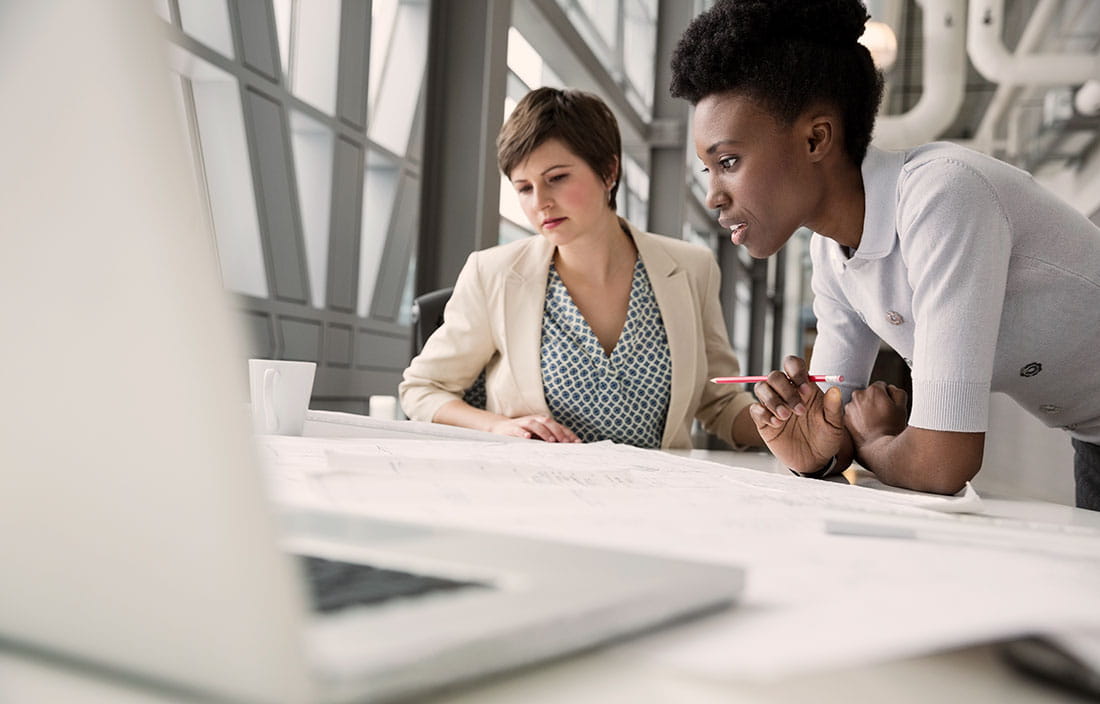 Two women in a meeting with a laptop in the foreground.