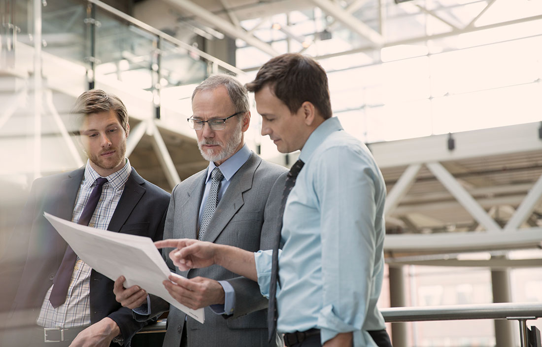 Three men looking at one document.