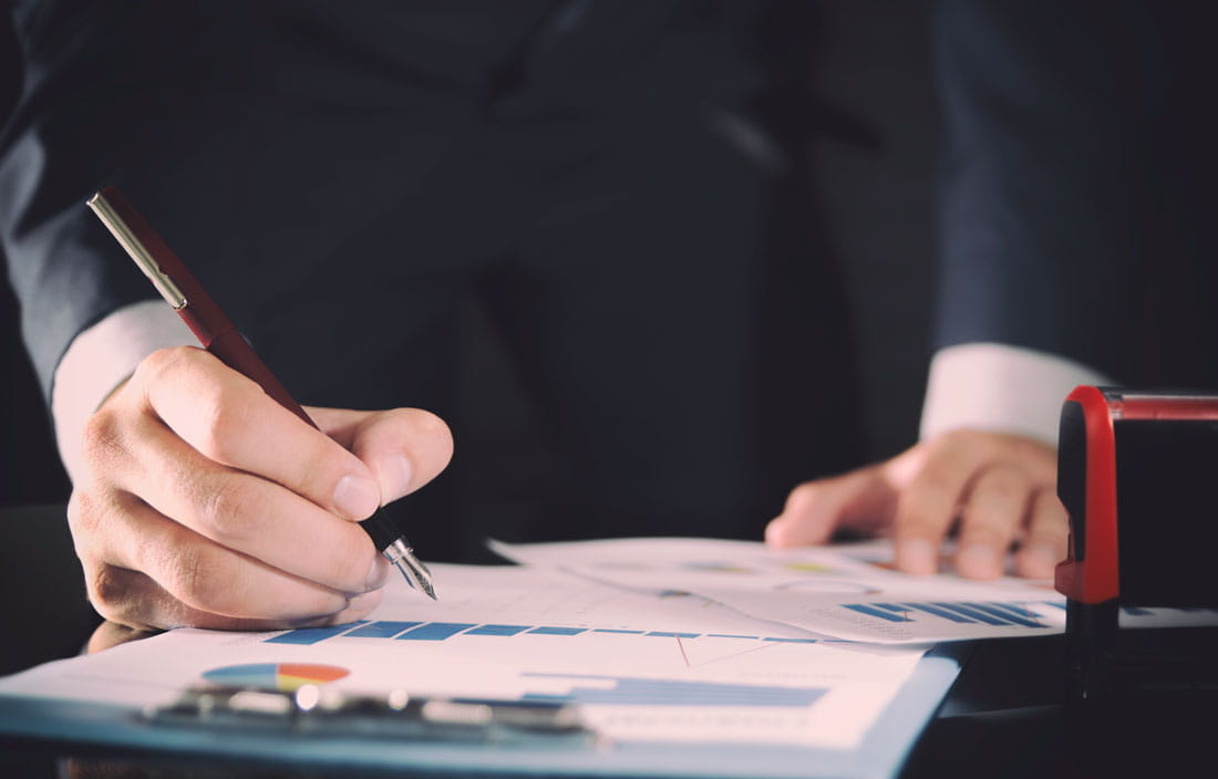 Image of hands holding pen over clipboard with graph.