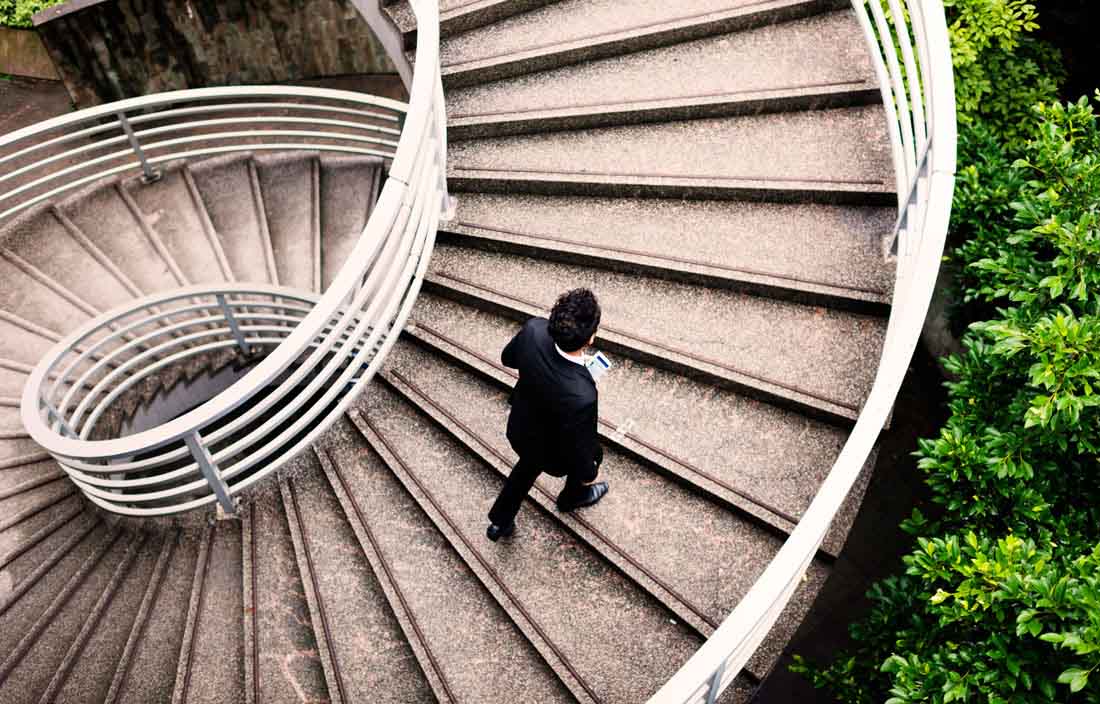 Image of man walking up outdoor spiral staircase.