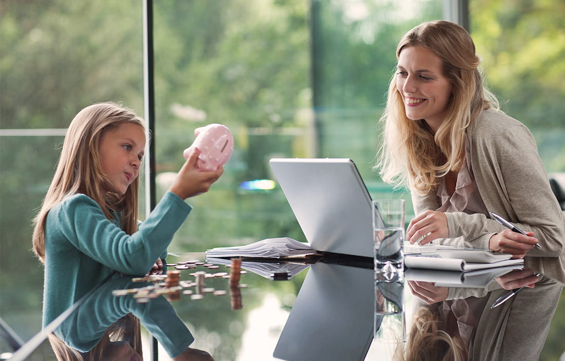 Photo of mom and daughter at table with piggy bank