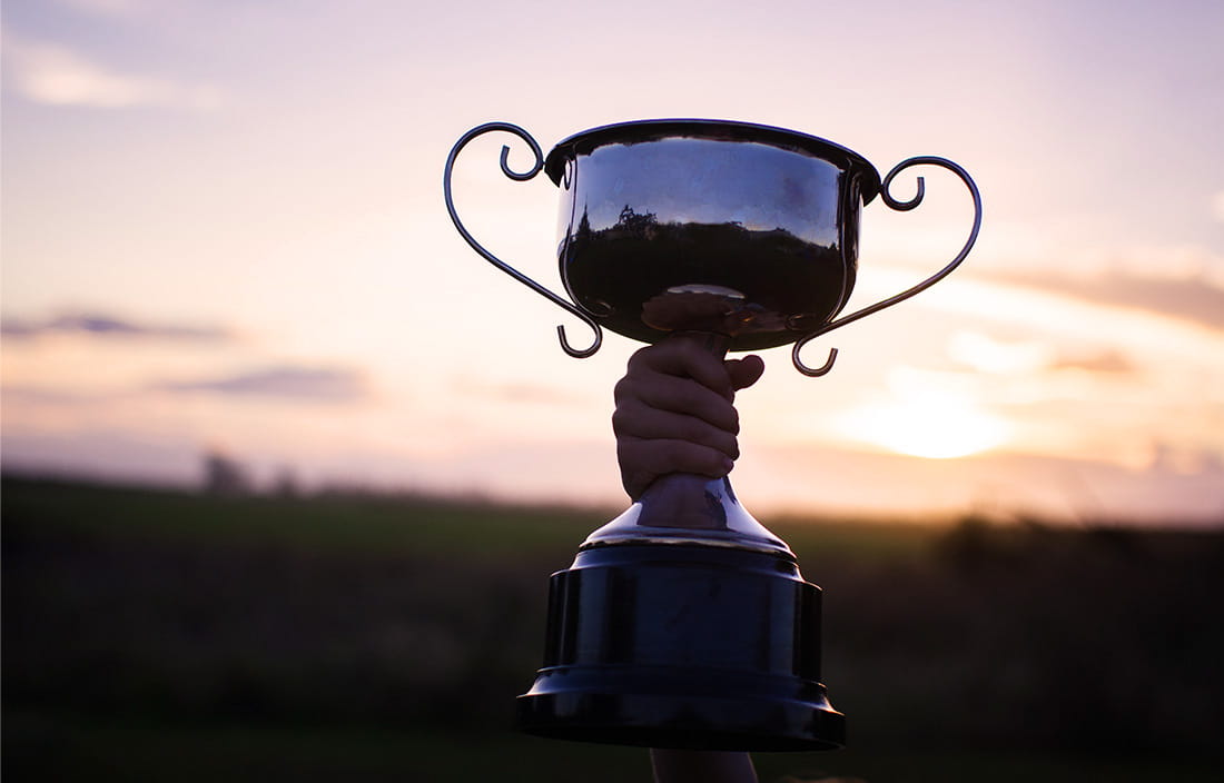 Image of hand holding trophy against sunset