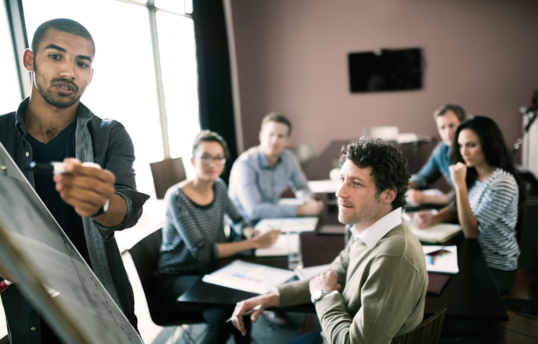 Image of staff in a meeting with one man writing on a flipchart.