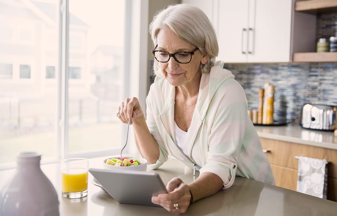 Woman eating breakfast and looking at her tablet