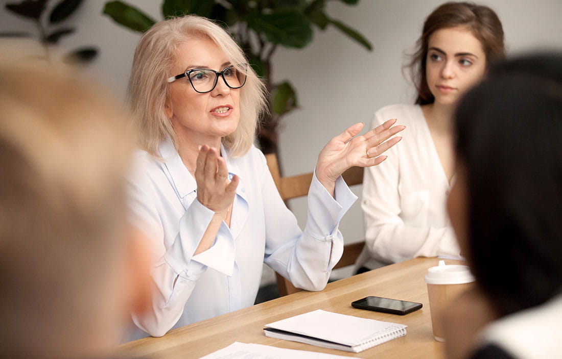 Women sitting in an office meeting with one speaking and one listening
