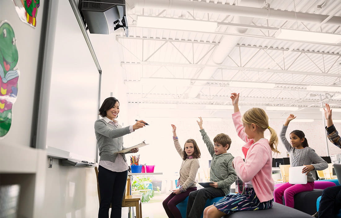 teacher in front of whiteboard and class of young students