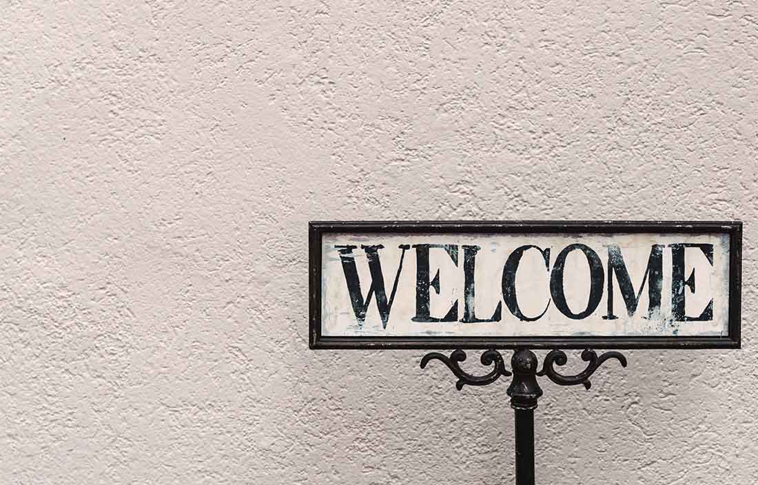 antique welcome sign against textured white wall