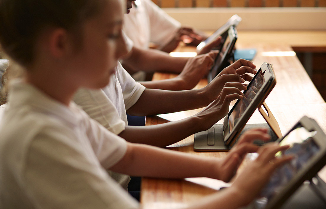 kids on tablets at a desk