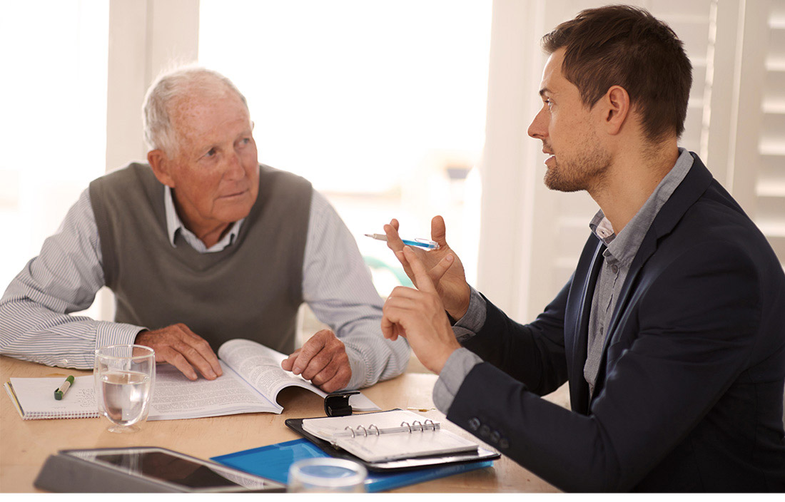 older man and younger man discussing something at a table