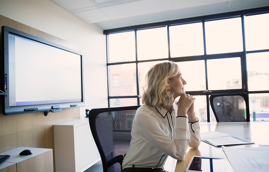 Image of woman sitting at a desk and looking out of a window