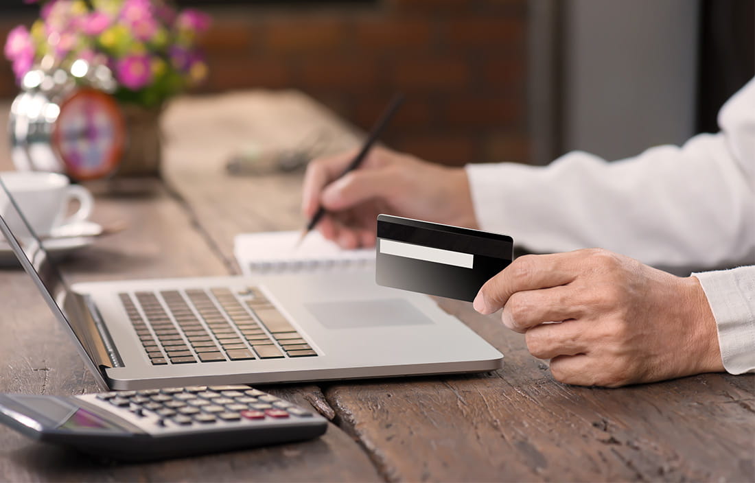 Image of man working on computer and holding a credit card