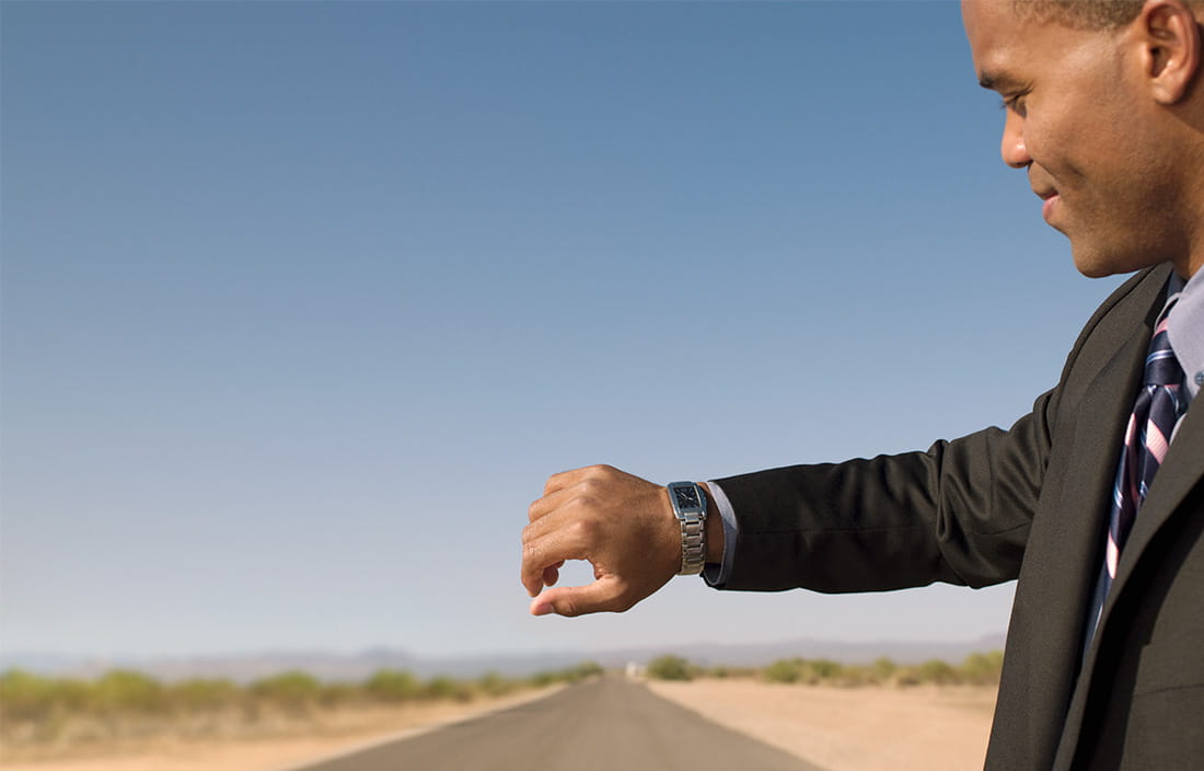 Image of a man looking at his watch on a desert road
