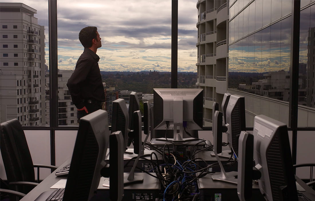 Image of man looking out window of an office building