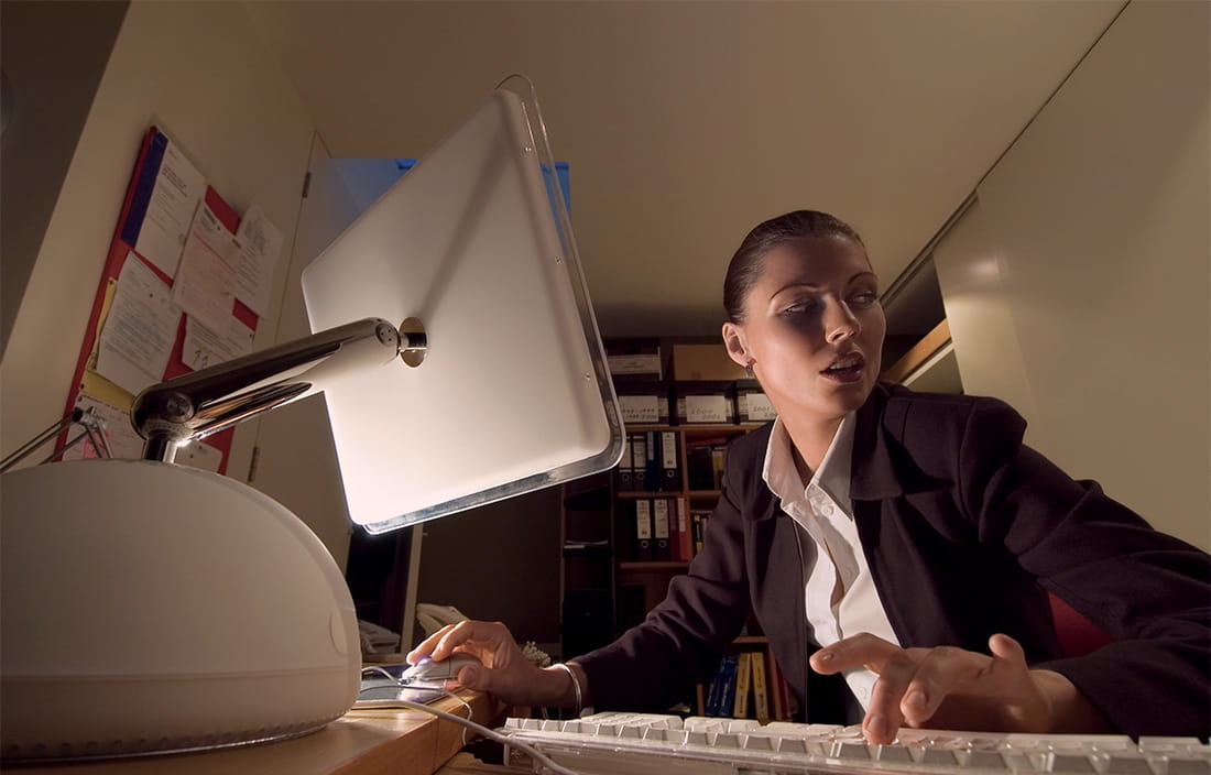 Image of woman on computer in dimly lit room