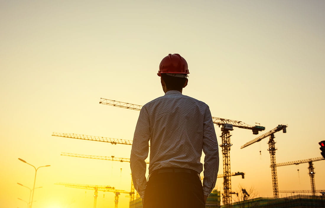 Engineer with crane background at sunset.