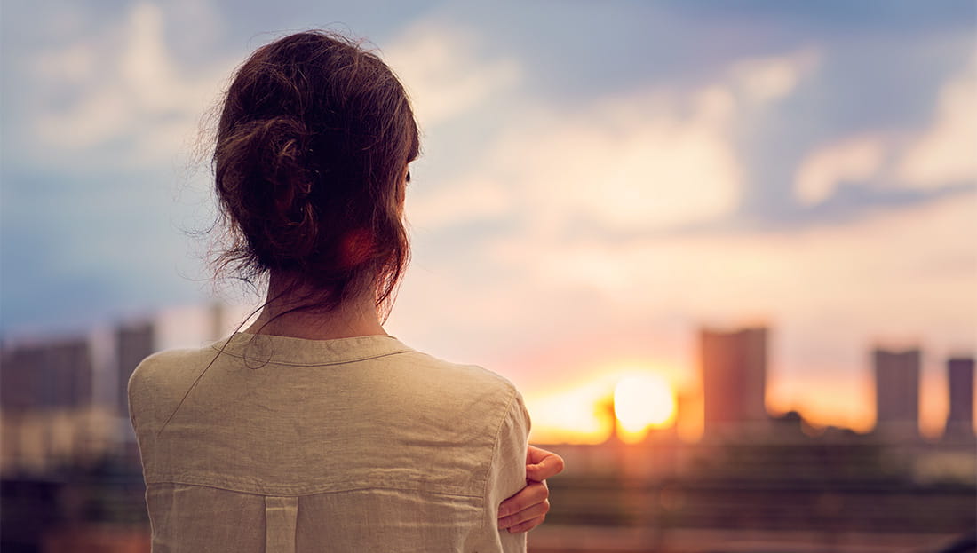 Woman watching the sunset over a cityscape