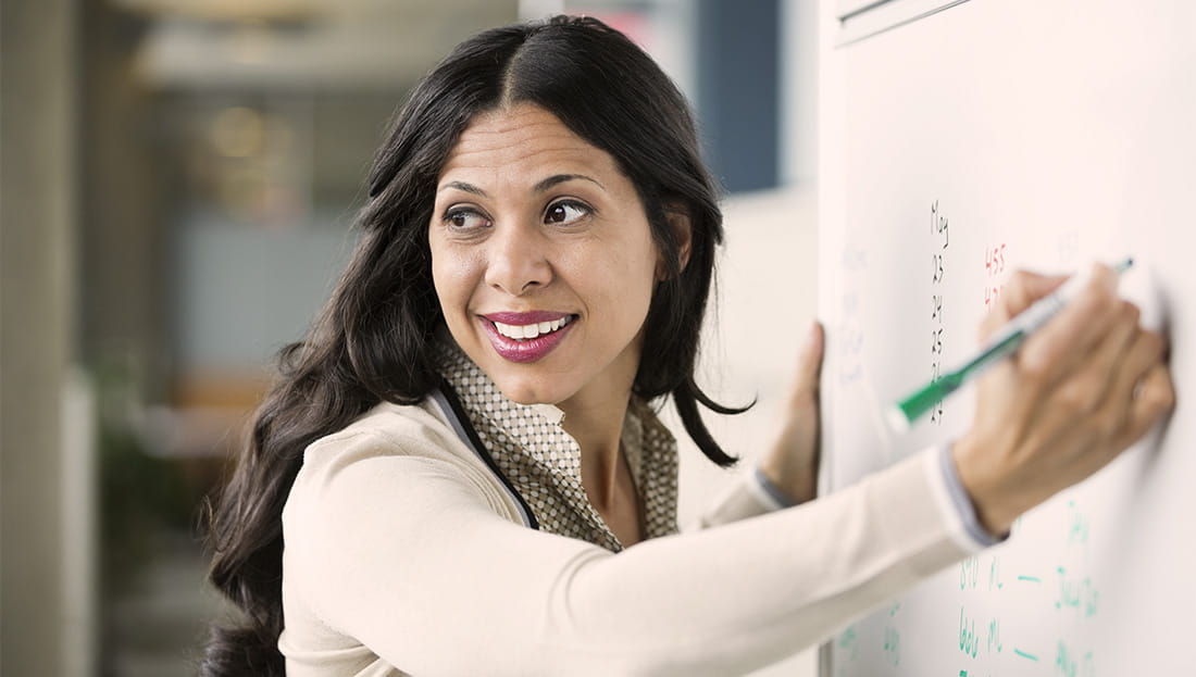 smiling woman writing on a whiteboard