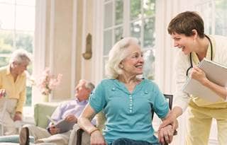 Senior woman cheerfully speaking with her female caretaker in a senior living facility
