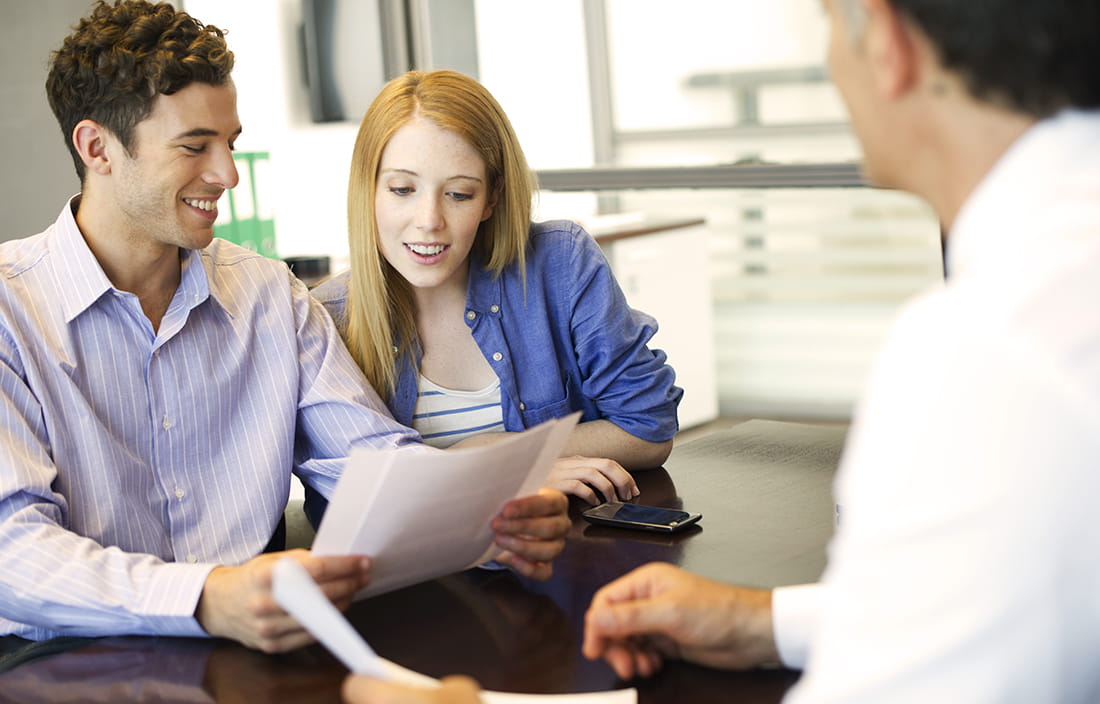 Man and a woman going over paperwork with another man at a desk