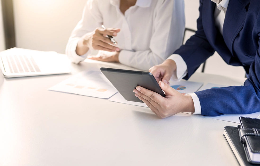 Man and woman sitting at a desk looking at a tablet