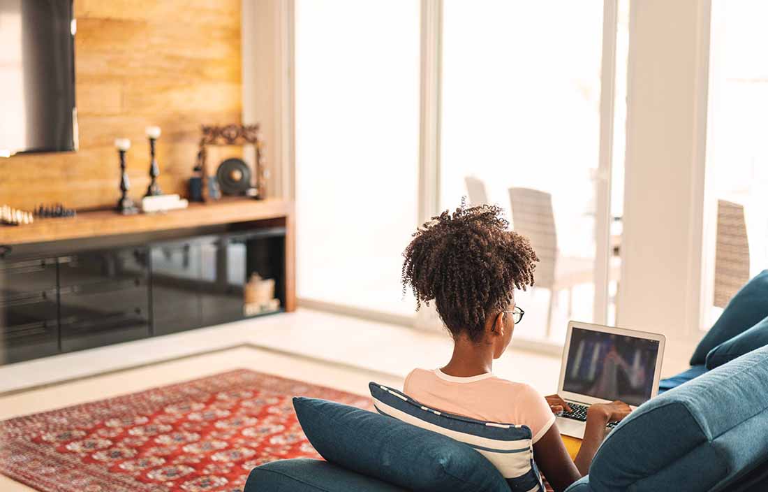 Woman sitting at home on a couch working on a laptop